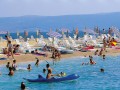 Crikvenica - perła chorwackiej riwiery


Crikvenica to niewielkie miasteczko, położone na chorwackim wybrzeżu około 35 km od Rijeki. Jest jednym z najstarszych kurortów w basenie Morza Śródziemnego i zapewnia turystom ponad 2500 słonecznych godzin w ciągu roku. Wraz z pobliską miejscowością Selce stanowi ważny punkt na turystycznej mapie Chorwacji. 


Historia


Historia miasta sięga Cesarstwa Rzymskiego. Znajdował się tu wówczas warowny, wojskowy obóz, który z biegiem czasu - po przybyciu Chorwatów - przekształcił się w osadę o nazwie Kotor. Osada na początku XV wieku została rozbudowana przez księcia Mikołaja IV Frankopana. Ufundowano wówczas, przy ujściu rzeki Dubračine kościół (w języku chorwackim crikva) Paulinów - Zakonu Świętego Pawła Pierwszego Pustelnika, od którego wywodzi się obecna nazwa miasta.

W 1760 roku Crikvenica stała się centrum administracyjnym dla całego obszaru Vinodol. Rozkwit miasta nastąpił jednak dopiero w XIX wieku, gdy Crikvenica stała się jednym z pierwszych kurortów, do którego tłumnie ściągali kuracjusze z Cesarstwa Austro-Węgier. Renoma doskonałej miejscowości wypoczynkowej przetrwała do dnia dzisiejszego - Crikvenica, po rozbudowie infrastruktury turystycznej stała się jednym z najważniejszych ośrodków wybrzeża Kvarner i całego północnego wybrzeża Chorwacji.


Atrakcje


Miasto stanowi część tzw. Riwiery Rijeki i Crikvenicy, pełnego atrakcji pasa nadmorskich miejscowości (Crikvenica, Selce, Novi Vinodolski i Senj), wartych potraktowania jako jedna, niezwykle atrakcyjna turystycznie całość.

W samej Crikvenicy zwiedzanie warto zacząć od miejsca, któremu miasto zawdzięcza swoją nazwę. Klasztor zakonu Paulinów, wraz z przylegającym do niego kościołem Błogosławionej Dziewicy Marii, został zbudowany w XV wieku. Szczególnie warta uwagi jest średniowieczna bryła budowli. Jej wnętrze zostało przebudowane - obecnie znajduje się tam hotel.

Aby lepiej poznać lokalną historię i tradycję, trzeba koniecznie odwiedzić Kotor. To najstarsza dzielnica Crikvenicy, pierwotnie samodzielna osada, która dała początek współczesnemu miastu. Wielu wrażeń dostarczają umieszczone w Kotorze stanowiska archeologiczne, jak również pozostałości średniowiecznych zabudowań. Można tam również zwiedzić ślady obwarowań miejskich oraz ruiny średniowiecznego kościoła.

Na miejscu można również skorzystać z licznych wycieczek - m. in. do Doliny Vinodolskiej, oraz wybrać się w rejs wzdłuż riwiery - wybrzeże widziane od strony morza prezentuje się bowiem niezwykle malowniczo.

Dzięki wycieczce do pobliskiego miasteczka Novi Vinodolski, można poznać historyczną przeszłość regionu. Miasteczko to przed wiekami było siedzibą znakomitych, chorwackich rodów - Frankopan i Zrinski, fundatorów miejscowych zabytków i kościołów. Miasto jest ośrodkiem turystycznym z niezwykłymi tradycjami - pierwszy kurort powstał tam w 1878 roku. Na miejscu można również skorzystać z hotelu, istniejącego od końca XIX wieku. Novi Vinodolski to również miejsce ważne dla chorwackiej historii - w 1288 roku powstał tam jeden z pierwszych w Europie kodeksów prawnych - Ustawa Vinodolska. W mieście warto również odwiedzić muzeum etnograficzne, zlokalizowane w XIII - wiecznych fortyfikacjach.

Na południe od Crikvenicy znajduje się niewielka miejscowość Dramalj. Na turystów czekają tam piękne plaże, jednak największą miejscową atrakcją jest toš - stary, drewniany młyn, wykorzystywany w dawnych czasach do mielenia oliwek. Współcześnie młyn niestety jest nieczynny, stanowi jednak świadectwo odwiecznej tradycji uprawy oliwek w tym regionie.

Spośród pobliskich atrakcji nie można pominąć wyspy Krk, jednej z najczęściej odwiedzanych na chorwackim wybrzeżu. Poza walorami krajobrazowymi na popularność wyspy wpływa z pewnością bardzo dogodna komunikacja - Krk połączona jest ze stałym lądem długim mostem, umożliwiającym przejście oraz przyjemny spacer. Odwiedzając Krk warto udać się do jaskini Biseruljka - położna głęboko pod powierzchnia, kryje w sobie wartą uwagi galerię, a przez jej wnętrze przepływa podziemny strumień.

Entuzjaści nieco dalszych wycieczek mogą również odwiedzić pobliską Rijekę. To trzecie co do wielkości miasto Chorwacji często porównywane jest z włoskim Triestem. Jego liczne zabytki oraz bogata infrastruktura turystyczna stanowią gwarancję dobrej rozrywki i wypoczynku.

Dla amatorów spacerów nie lada gratką będzie nadmorska promenada, łącząca z Crikvenicą miejscowości Selce i Kačjak. Trasę liczącą około 8 kilometrów można, niespiesznym tempem, pokonać w około 3 godziny. Położona przy promenadzie miejscowość Selce to lokalne centrum rekreacji. Posiada bardzo dobre warunki i zaplecze, pozwalające na aktywny wypoczynek. Coś dla siebie znajdą tu miłośnicy joggingu, rolek i wycieczek rowerowych. W pobliżu znajdują się również pola do minigolfa oraz przystań jachtowa. Amatorzy spokojnej kąpieli z pewnością docenią zatoki Selce i Slane. W przeciwieństwie do Crikvenicy, miasta nastawionego na rozrywkę, miejscowość Selce zachowała klimat i charakter sennej osady rybackiej, stanowiąc doskonałą ofertę dla wszystkich, szukających miejsca na spokojny, rodzinny wypoczynek.


Kulinaria


Miasto oferuje pełen przekrój dań, charakterystycznych dla kuchni tego regionu. Wśród nich na uwagę zasługują m. in. tort Frankopan - tradycyjny przysmak, zgodnie z legendą nawiązujący do potężnej niegdyś rodziny, władającej całym regionem. Na zwolenników owoców morza czekają krewetki w winie - podawane z opiekanym chlebem - tradycyjny przysmak miejscowych marynarzy. Warto również skosztować lokalnego specjału - ryb gotowanych z czosnkiem, winem, oliwą, selerem i marchwią.


Komunikacja


Szybką komunikację ze światem zapewnia lotnisko w nieodległej Rijece. Znajdują się tam również przystanie promowe. Transport z Rijeki do Crikvenicy i innych miejscowości riwiery zapewniają często kursujące autobusy. Zwolennicy samodzielnych wyjazdów mogą natomiast bez problemu dotrzeć do Crikvenicy własnym samochodem - pokonując około 150 km autostradą z Zagrzebia.


Rozrywka


Crikvenica, podobnie jak inne miasta riwiery, to doskonałe miejsce do plażowania. Wyjątkowe walory krajobrazowe i pełne uroku plaże zachęcają do kąpieli. Trzeba jednak pamiętać o specyfice chorwackich plaż - zamiast piasku przeważają tam drobne kamienie. Wszyscy, którzy uwielbiają kąpiele w morzu nie będą jednak zawiedzeni - czeka na nich ciepła i przejrzysta woda. Dogodne warunki dla siebie znajdą tu ponadto amatorzy nurkowania. W Crikvenicy znajduje się również przystań i klub żeglarski.

W mieście cyklicznie organizowana jest również parada maszkar oraz zloty miłośników starych motocykli. Niezwykłą atrakcją - także dla najmłodszych - jest, położone przy ulicy Vinodolskiej, akwarium morskie. Na spragnionych rozrywki turystów czekają również liczne bary i dyskoteki, często umiejscowione tuż przy zejściu na plażę.