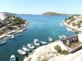 Trogir to piękne, portowe miasteczko, położone w Chorwacji w regionie Środkowej Dalmacji, na wybrzeżu Adriatyku. Jego niezwykła historia i liczne, warte zobaczenia zabytki sprawiają, że nazywane jest miastem - muzeum. Niewątpliwym atutem Trogiru jest jego malownicze położenie - najstarsza, historyczna część miasta zajmuje niewielką wysepkę, strzegącą cieśniny pomiędzy wybrzeżem Dalmacji a wyspą Čiovo.


Historia


Historia Trogiru zaczęła się w III wieku p. n. e., gdy przybyli z wyspy Vis (która wówczas nazywała się Issa) greccy koloniści, założyli osadę o nazwie Tragurion, czyli Kozie Wzgórza. Osada z czasem przekształciła się w portowe miasto, które jednak nie odgrywało istotnej roli w regionie.

Rozkwit nastąpił dopiero w XII wieku. Czasy świetności miasta poprzedził jednak najazd Saracenów, którzy doszczętnie zburzyli Trogir. Odbudowane z gruzów miasto zaczęło się jednak szybko rozwijać, stając się od XIV wieku ważnym ośrodkiem gospodarczym i kulturalnym Dalmacji. Stabilizacji sprzyjał długi okres, w którym miasto pozostawało pod panowaniem śródziemnomorskich mistrzów handlu i wojennego rzemiosła - Wenecjan. Upadek Republiki Weneckiej w 1797 r. spowodował, że Dalmacja, a wraz z nią Trogir, weszły - do 1918 roku - w skład Monarchii Habsburskiej.

Po zakończeniu pierwszej wojny światowej Dalmacja stała się częścią Królestwa Serbów, Chorwatów i Słoweńców, znanego również pod nazwą Królestwa SHS, które w 1929 roku przekształciło się w Jugosławię. Od rozpadu Jugosławii w 1991 roku Trogir należy do Chorwacji.


Atrakcje


Przez ponad 2300 lat istnienia, Trogir stał się niesamowitym konglomeratem kultur i stylów architektonicznych. Wyjątkową atrakcją miasta - unikalną w skali całego świata, jest doskonale zachowana starówka, łącząca style romańskie i gotyckie. Zabytek ten został w 1997 roku wpisany na listę światowego dziedzictwa UNESCO.

Aby podziwiać uroki starej części miasta, trzeba najpierw przejść przez umieszczoną w doskonale zachowanych murach miejskich, XVI-wieczną Bramę Lądową. Brama ta, ozdobiona niegdyś weneckim lwem św. Marka była symbolem panowania Wenecjan nad Trogirem. Obecnie patronuje jej bł. Jan z Trogiru.

Spacerując wąskimi uliczkami starego miasta nie sposób pominąć zamku Kamerlengo - weneckiej budowli, strzegącej niegdyś cieśniny pomiędzy Trogirem a wyspą Čiovo. Grube mury tej budowli dobitnie pokazują, jaką wagę przywiązywali Wenecjanie do obrony wybrzeża przed najeźdźcami. Zgodnie z lokalną tradycją to właśnie w tym zamku mocowano linę, która łącząc wyspę ze stałym lądem stanowiła nietypową przeszkodę dla próbujących przepłynąć statków. Obraz nadmorskich umocnień uzupełnia baszta św. Marka. Umieszczone na niej armaty pozwalały Wenecjanom kontrolować ruch statków, chcących przepłynąć między Čiovo a wybrzeżem Dalmacji.
 
Droga spod zamku do głównej części miasta wiedzie promenadą Bana Berislavica, wzdłuż której koncentrują się lokalne kafejki i knajpki. Swojego imienia dla promenady udzielił urodzony w Trogirze ban - władca dalmacki, który na początku XVI wieku zasłynął zwycięskimi walkami z tureckim najeźdźcą.

Największe atrakcje Trogiru skupione są w pobliżu placu Jana Pawła II. Wśród nich prym wiedzie katedra św. Wawrzyńca - jedna z nielicznych zachowanych w Chorwacji romańskich katedr. Wyjątkową ozdobą budowli jest monumentalny portal - ozdobne wejście, uznawane za jeden z najpiękniejszych przykładów rzeźby romańskiej na wybrzeżu Adriatyku. Powodem do dumy dla lokalnych patriotów jest autor tego dzieła - mistrz Radovan, XIII-wieczny dalmacki rzeźbiarz i architekt, który urodził się właśnie w Trogirze. Atrakcją katedry są również wzniesione w różnych stylach architektonicznych dzwonnice oraz kaplica bł. Jana z Trogiru, którą renesansowy rzeźbiarz, Nicola Firentinac upiększył ponad stu pięćdziesięcioma rzeźbami postaci ludzkich.

Poza katedrą warto również zwrócić uwagę na miejską loggię, w której umieszczono dwie rzeźby - współczesną, z 1950 roku, dłuta Ivana Mestrovica i historyczną - Sprawiedliwość dłuta Nicoli Firentinaca z 1471 r. Spacerując po placu Jana Pawła II warto również zwrócić uwagę na wieżę zegarową i miejski ratusz wzniesiony w stylu romańsko - gotyckim.

Gratką dla poszukiwaczy nietypowych miejsc jest klasztor Benedyktynów - poza walorami architektury, budowla ta kryje w sobie nietypową niespodziankę - w przyklasztornym muzeum znajduje się wizerunek greckiego boga Kairosa, uskrzydlonego młodzieńca, odpowiadającego za szczęśliwe zbiegi okoliczności. Według greckiej mitologii, Kaiors przemieszczał się bardzo szybko - ten, kogo mijał miał tylko krótką chwilę, by go pochwycić, a razem z nim swoją życiową szansę.

Kolejną wartą uwagi turystyczną atrakcją miasta jest pałac Cipiko, wzniesiony w 1457 roku dla najznamienitszej wówczas rodziny trogirskiej o tym nazwisku. Warto w tym miejscu zauważyć, że wszystkie te atrakcje skupione są na bardzo małej, niewymagającej dłuższych spacerów przestrzeni - jak przed kilkuset laty pracowicie obliczył historyk Pavao Andreis, cała starówka liczy zaledwie 750 kroków!


Komunikacja


Zaletą Trogiru jest jego dogodne - z punktu widzenia urlopowego wyjazdu - położenie. Zaledwie sześć kilometrów od miasta znajduje się Lotnisko Split, z którego regularnie kursującymi autobusami można dostać się zarówno do Trogiru, jak i do Splitu. Poza autobusami można również skorzystać z usług licznych w okolicy lotniska taksówek, można również na czas urlopu wynająć samochód z wypożyczalni w odległym o ok. 25 km Splicie. Dodatkowo w najbliższych latach planowana jest rozbudowa linii kolejowej, która połączy Split, Trogir i lotnisko.


Specjały kulinarne


Kuchnia, której można skosztować w Trogirze, jest typowa dla wybrzeża Dalmacji. Amatorzy dobrego jadła mogą w licznych knajpkach delektować się tradycyjnymi specjałami - w menu znajdą wiele dań przyrządzanych przy wykorzystaniu owoców morza, świeżych ryb (a szczególnie dorsza), jagnięciny i oliwy z oliwek. Gamę wrażeń smakowych uzupełnia doskonała wędzona szynka i ser marynowany w oliwie. Można również skosztować wybornego wina z pobliskich, ekologicznych winnic.
 
Warto w tym miejscu wspomnieć, że woda płynąca w miejskich wodociągach Trogiru pochodzi z tego samego źródła, z którego w starożytności zaopatrywano słynny Pałac Dioklecjana w Splicie. Pałac ten, podobnie jak trogirska starówka, znajduje się na liście światowego dziedzictwa UNESCO.


Rozrywka


Najbardziej znanym współcześnie Chorwatem, który urodził się w Trogirze, jest Vinko Coce - słynny tenor, z którego inicjatywy w mieście corocznie odbywa się międzynarodowy Festiwal Tenorów. W czasie wakacji można również podziwiać występy organizowane podczas Letniego Festiwalu Kultury oraz spektakle wystawiane w Pałacu Książęcym. Dla wielbicieli muzyki nie lada atrakcję stanowi baszta św. Marka, która ze względu na zgromadzone w niej zbiory nazywana jest obecnie „domem muzyki dalmatyńskiej”.

Amatorzy aktywnej rozrywki mogą skorzystać z dostępnej w Trogirze wypożyczalni quadów, motocykli i samochodów buggy, które z pewnością dostarczą wielu atrakcji podczas zwiedzania okolicy przystosowanymi dla tych pojazdów szlakami.

Urok pełnego zabytków miasta, piękno okolicy, jak również bliskość innych atrakcji Środkowej Dalmacji sprawiają, że Trogir znajduje się wysoko na liście miejsc, które warto zobaczyć podczas wycieczki do Chorwacji.