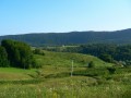 Oštarski Stanovi to niewielka miejscowość położona na pogórzu Gór Dynarskich w centralnej Chorwacji. Miejscowość ta leży w spokojnej okolicy, której krajobraz to łagodne wzgórza, lasy, sady i wsie, malowniczo poprzecinane dolinami strumieni i rzek. Zaletą jest bliskość przejścia granicznego z Bośnią i Hercegowiną - wakacje w na pogórzu Gór Dynarskich to doskonała okazja, by przy okazji poznać choć trochę ten wyjątkowy, choć jeszcze dość anonimowy kraj.


Historia


W starożytności ziemie, na których znajduje się miejscowość Oštarski Stanovi należała do rzymskiej prowincji Iliria. Zamieszkiwali ją Ilirowie, których potomkami są dzisiejsi Albańczycy i Rumuni. Niedługo po podziale Ilirii na Panonię i Dalmację, na tereny te zaczęli napływać Słowianie z obszaru dzisiejszej Polski i Ukrainy. Słowiańscy Chorwaci, którzy się tutaj osiedlili, posiadali przez krótki okres własne państwo (Królestwo Chorwacji), które szybko dostało znalazło się najpierw pod wpływami, a potem pod rządami Węgier. Po średniowieczu w Chorwacji mieszały się wpływy węgierskie, weneckie i niemieckie (austriackie). Ponadto ziemie na których znajduje się miejscowość Oštarski Stanovi były strefą buforową, odgradzającą Imperium Osmańskie od reszty Europy. Stąd liczne tutaj zamki, twierdze lub ich pozostałości. Słowiańscy mieszkańcy tych ziem uzyskali niezależność dopiero po I wojnie światowej (Królestwo SHS, Jugosławia) i utrzymali ją także po II (Jugosławia). W roku 1991 Chorwacja ogłosiła niepodległość, a tereny przy granicy z dzisiejszą Bośnią (wówczas Jugosławią), m.in. okolice Plitvic, stały się przedmiotem sporu między Chorwatami a bośniackimi Serbami.


Atrakcje turystyczne


Największą atrakcją turystyczną w okolicy jest Park Narodowy Jezior Plitvickich (Plitvička jezera), którego skarbem jest 16 jezior krasowych połączonych ze sobą licznymi wodospadami. Zwiedzać Park można kilkunastu różnymi trasami, na których są odcinki do pokonania pieszo, niewielkimi statkami pasażerskimi oraz pociągami drogowymi. Trasy przygotowane są i oznakowane tak, aby dostosować ich stopień trudności do indywidualnych możliwości turystów: najkrótsze z nich zajmują do 2 godzin wędrówki, najdłuższe - do 8. Ceny biletów wstępu nie zależą od wybranej trasy: turysta może wykupić bilet jednodniowy (110 kun) albo dwudniowy i w ramach tego terminu zwiedzać park dowolnymi trasami. Niedozwolone jest jednak opuszczanie oznakowanych ścieżek, a także biwakowanie, rozpalanie ognisk, łowienie ryb, kąpiel w jeziorach itp.


Wycieczki fakultatywne


Do miejscowości Oštarski Stanovi najlepiej przyjechać samochodem. Zabranie z sobą roweru jest jak najbardziej wskazane. Pozwoli to na swobodne poruszanie się po okolicy. Jednak do okolicznych miasteczek lepiej wybrać się samochodem. Warto polecenia są miejscowości takie jak: Sunj (15 km, m.in. malownicze wodospady rzeki Slunjčicy), Karlovac (klasztor franciszkanów, zamek, muzeum w ładnym renesansowym budynku), Ogulin (60 km, imponujący zamek), Klokoč (ok. 40 km, ruiny średniowiecznego zamku) i Bihać (ok. 20 km, miasto w Bośni, tuż przy granicy, pięknie położonym nad rzeką Uną, z twierdzą, urokliwym rynkiem i zabytkowym, kamiennym meczetem). Nad Adriatyk jest nieco dalej - ok. 105 km do miasteczka Senj, ale po drodze zobaczyć można ruiny kilku zamków, jezioro Gusić i malowniczą dolinę rzeki Gacki (m.in. młyny na Majerovym vrilu) - wszystko to w okolicy miasta Otočac (63-70 km).

Jeżeli pojedziemy do Oštarskich samochodem, po drodze będziemy mieć okazję, by zatrzymać się w trzech europejskich stolicach - Zagrzebiu, Wiedniu i Bratysławie. Po drodze są też takie miasta jak czeskie Brno i austriacki Graz.


Plaże i sporty


Okolicę tę można polecić osobom lubiącym odkrywać nowe miejsca przy pomocy roweru. Tereny te są odpowiednie dla przeciętnych i średnio zaawansowanych rowerzystów/kolarzy (bardziej górskich niż szosowych). Brak dużych miast, małe, spokojne wsie urokliwie położone wśród wzgórz i lasów, doliny małych rzek - trudno o miejsce bardziej sprzyjające uprawianiu turystyki rowerowej.


Noclegi


W miejscowości Oštarski Stanovi jest kilka zadbanych pensjonatów podobnych do polskich kwater agroturystycznych. Tego typu obiekty są bardzo częste w okolicy. W sumie Oštarski Stanovi dysponują ok. 30 miejscami noclegowymi.


Kuchnia


Odwiedzając kontynentalną Chorwację koniecznie należy skosztować smacznej wędzonej wędliny, smalcu ze skwarkami, turoša (rodzaj sera z krowiego mleka) z regionu Međimurje, podrawskiego wędzonego sera, rosołu z kury z makaronem domowej roboty, samoborskich kiełbasek czosnkowych z musztardą, kaszanki zapiekanej w kiszonej kapuście, zagórskiej indyczki z mlincami (mlinci to prosta potrawa mączna), paprykarza rybnego, gulaszu myśliwskiego, fasoli z rzepą, kaczki nadziewanej kaszą gryczaną, pieczeni wieprzowej, nadziewanej śliwkami polędwicy i koniecznie chorwackich zapiekanych naleśników z serowym nadzieniem i polanych śmietaną. Natomiast w Bośni warto spróbować tutejszej kawy po turecku, którą mieszkańcy tego kraju piją niemal nałogowo.


Klimat, pogoda, średnie temperatury


Kontynentalna część Chorwacji charakteryzuje się klimatem zbliżonym do polskiego, choć temperatury są o kilka stopni wyższe niż w Polsce. Sprzyja to przyjazdom również poza sezonem, kiedy w Polsce pogoda jest już nienajlepsza.